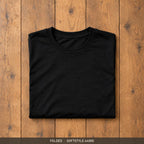 Black Gildan Softstyle 64000 t-shirt, neatly folded on a wooden floor
