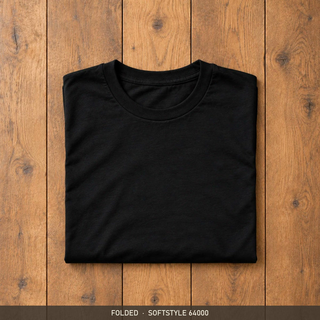 Black Gildan Softstyle 64000 t-shirt, neatly folded on a wooden floor