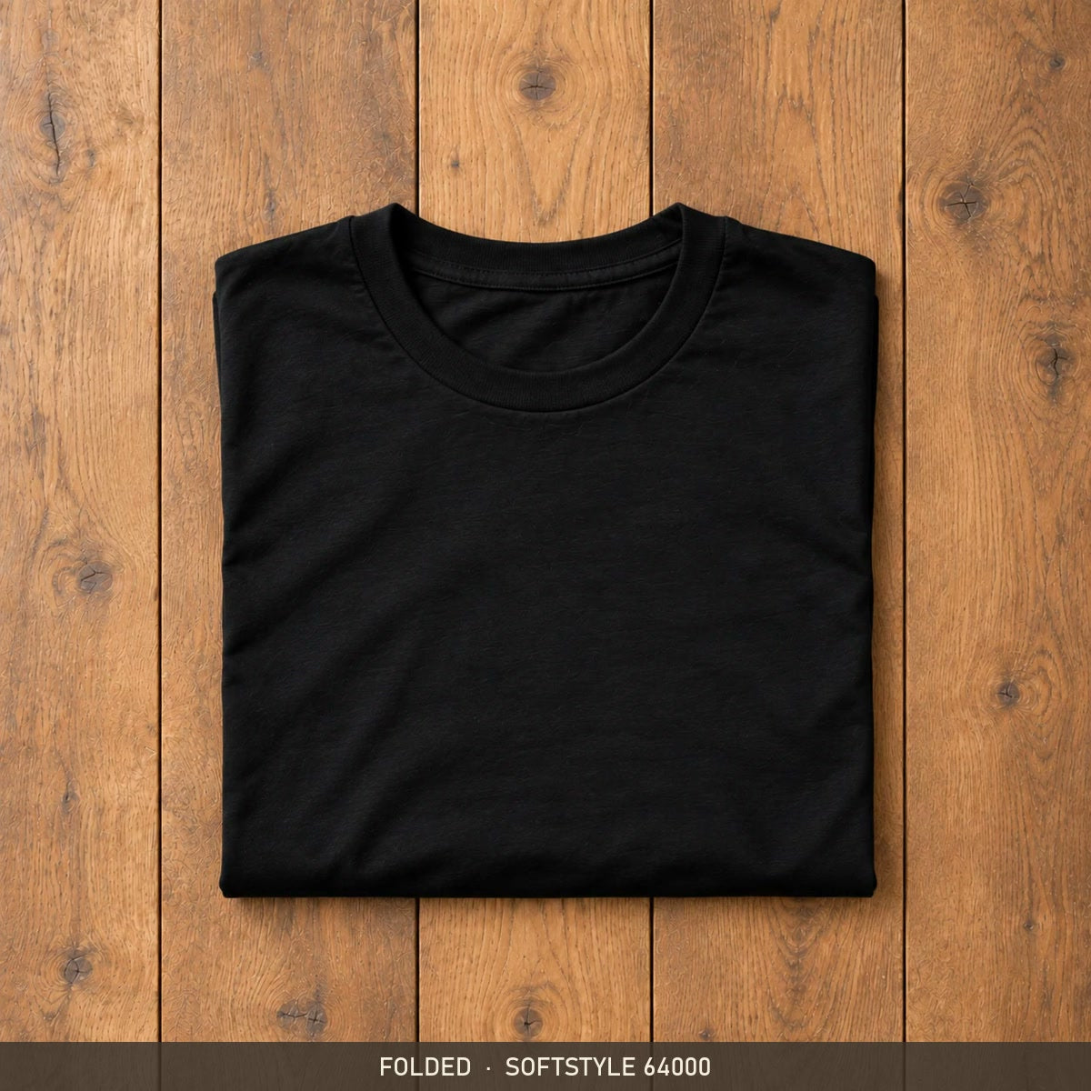 Black Gildan Softstyle 64000 t-shirt, neatly folded on a wooden floor
